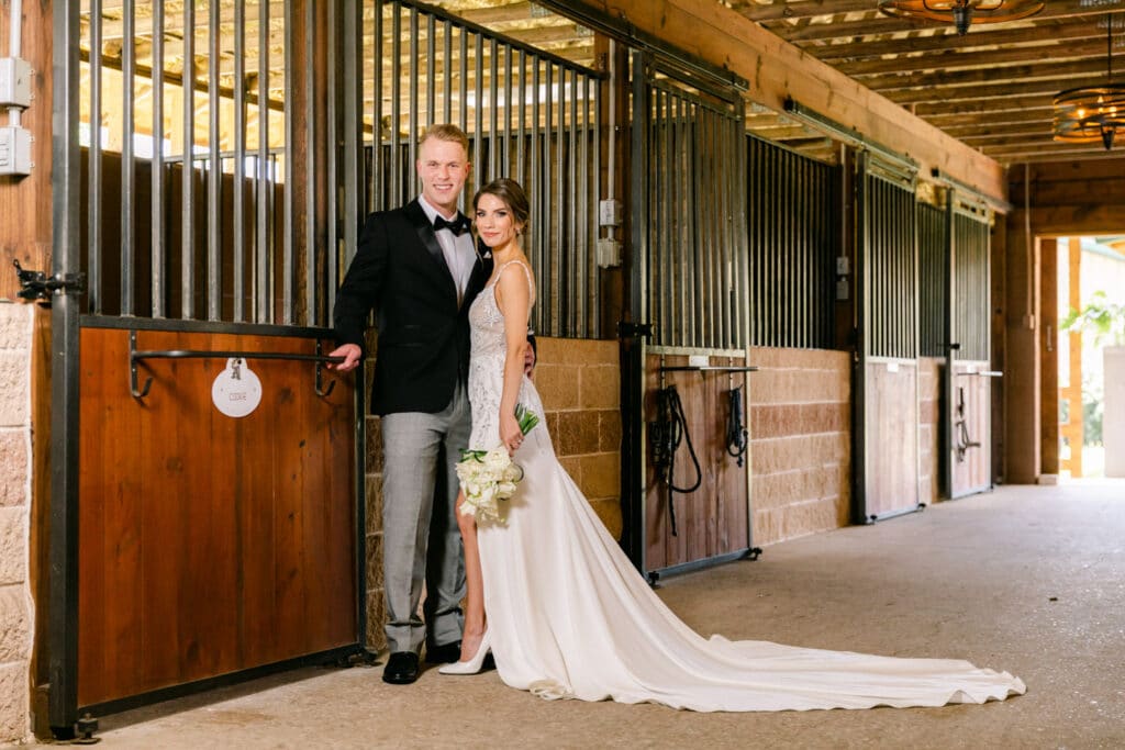A bride and groom embracing at a stable