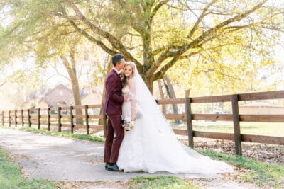 Bride and groom portrait along a rustic wooden fence path surrounded by golden autumn trees at BLB Hacienda wedding venue in Mount Dora Central Florida
