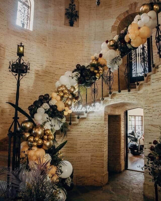 Side winding staircase adorned with balloon and floral garland