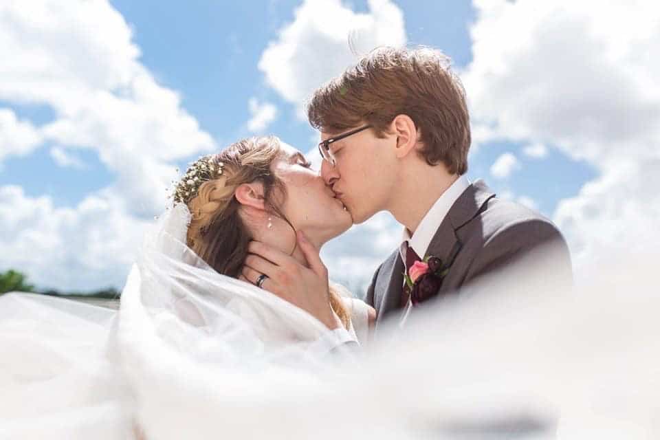 bride and groom kissing with blue sky background
