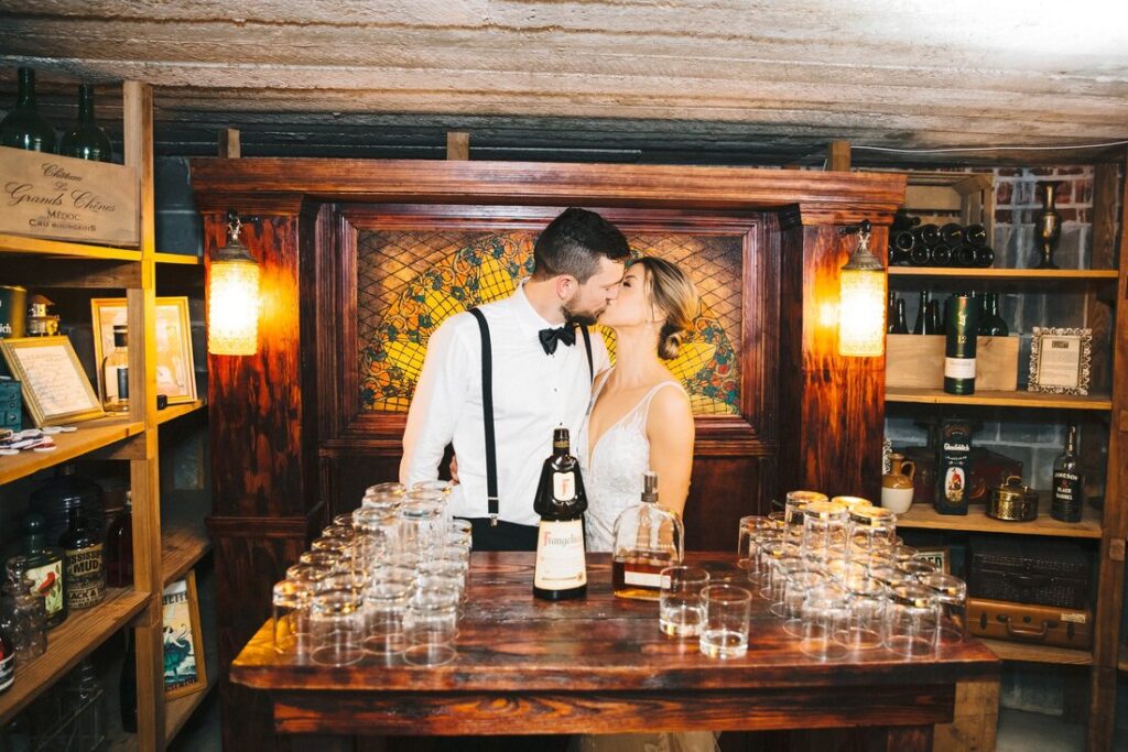 A bride and groom kissing behind the bar