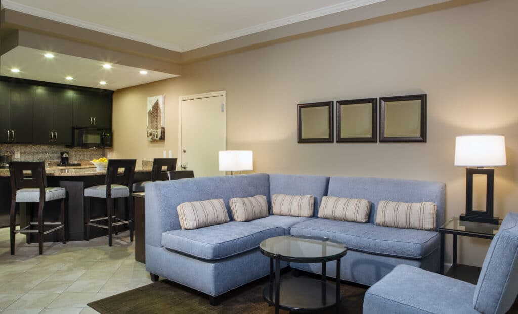 hotel suite with blue sectional sofa and open kitchen