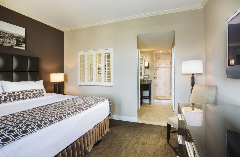 hotel suite with king bed with leather headboard and large bathroom