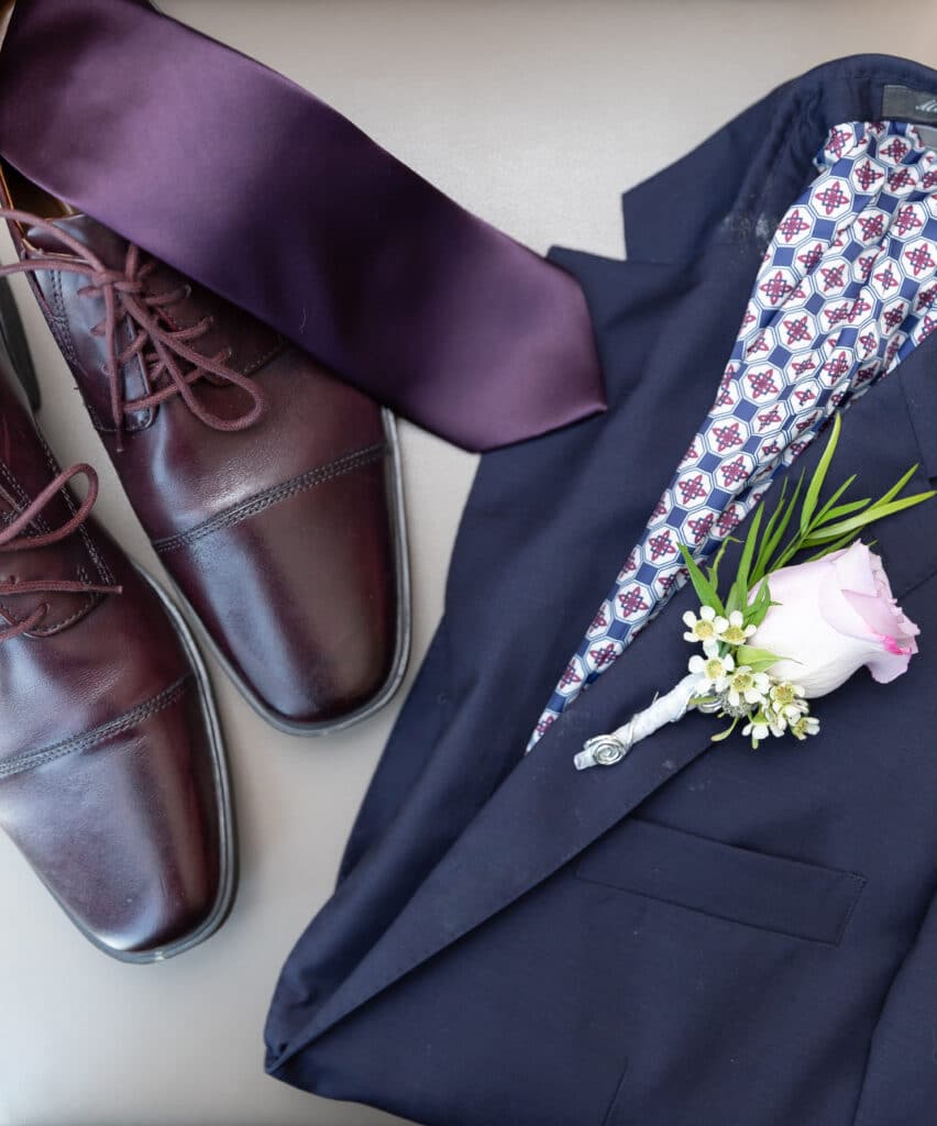 Gentleman's navy suit with purple accent and pink rose bud boutonniere