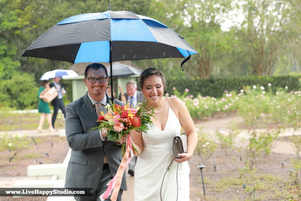 Groom holding umbrella for his bride