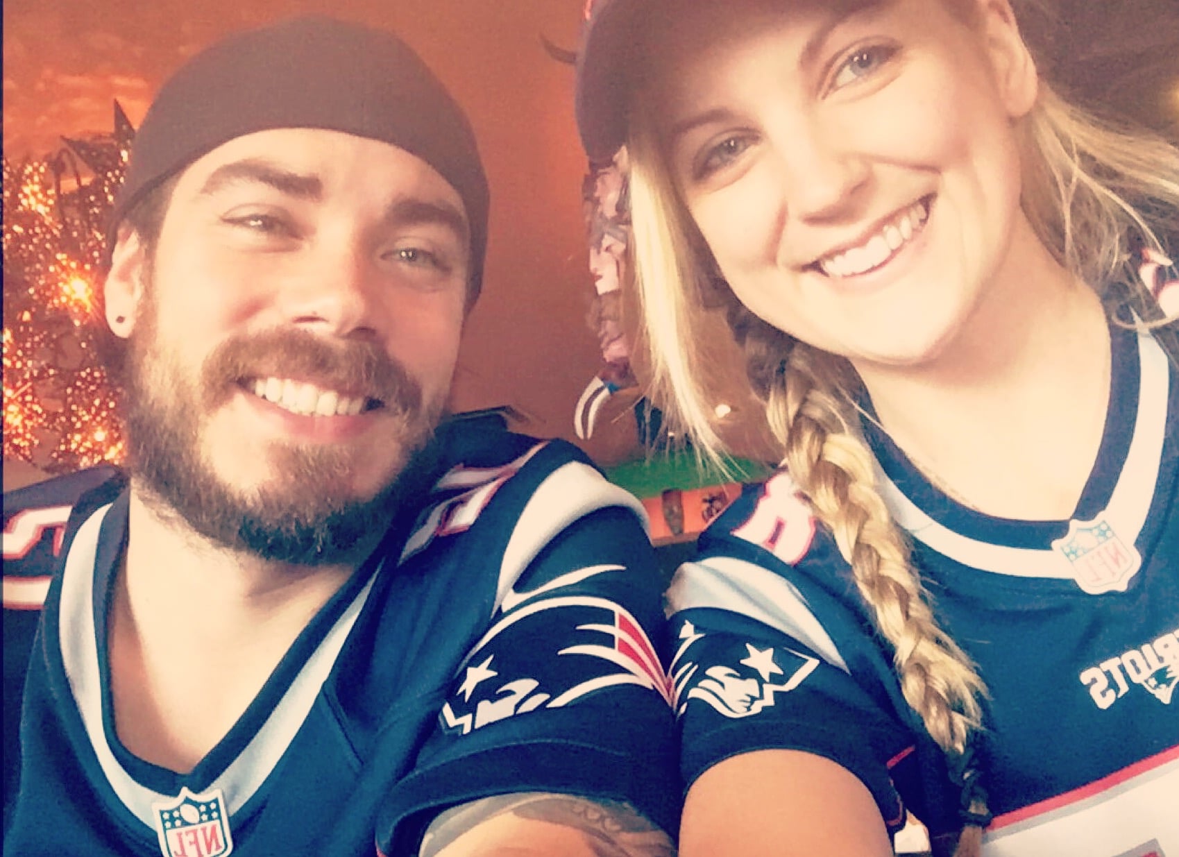bride and groom to be smiling and wearing football jersey.