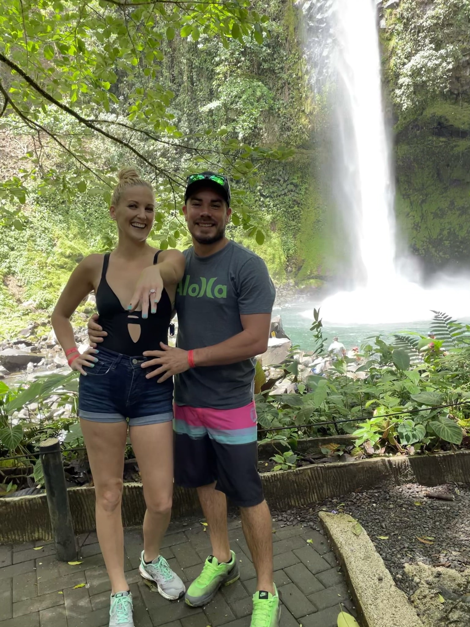 bride showing off her new engagement ring with her groom standing next to her smiling after their costa rica waterfall marriage proposal.