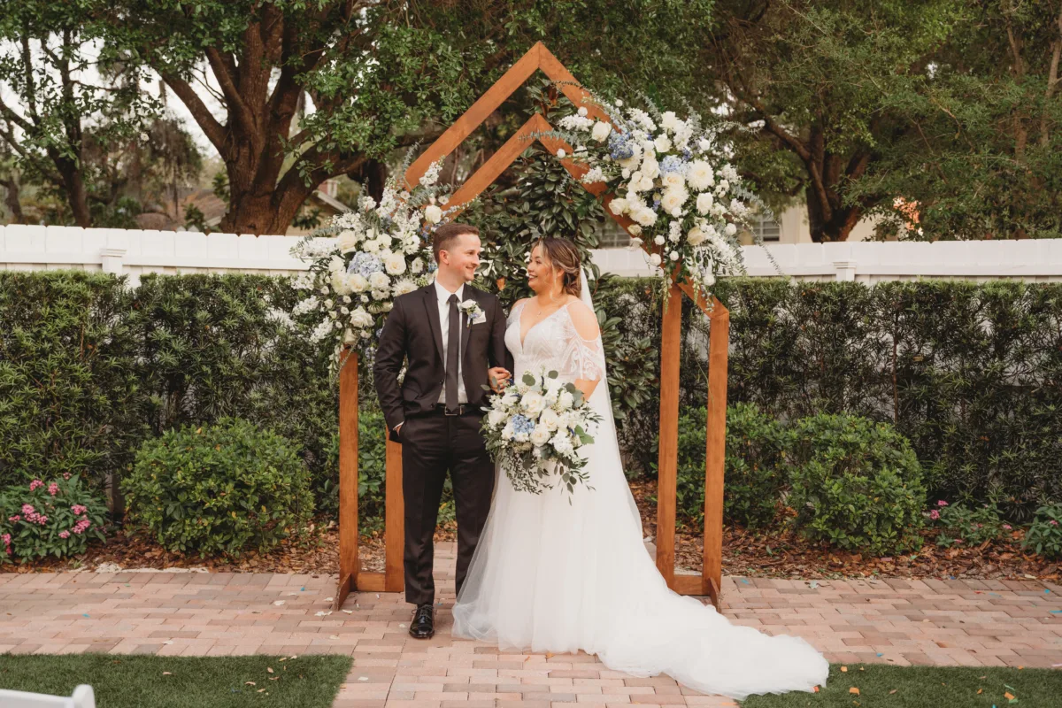 Elegant wedding sweetheart table with a geometric copper arch and lush white and blue floral arrangements.