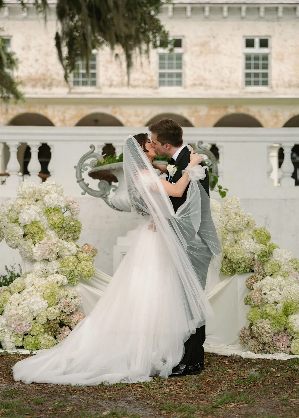 Couple getting married surrounded by beautiful floral arrangements and draping