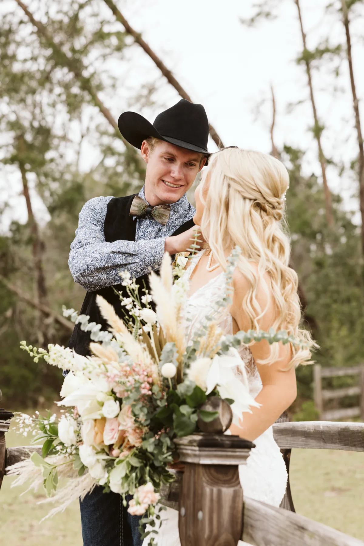 Bride and groom at an outdoor rustic wedding with lush neutral florals, pampas grass, eucalyptus, and greenery.