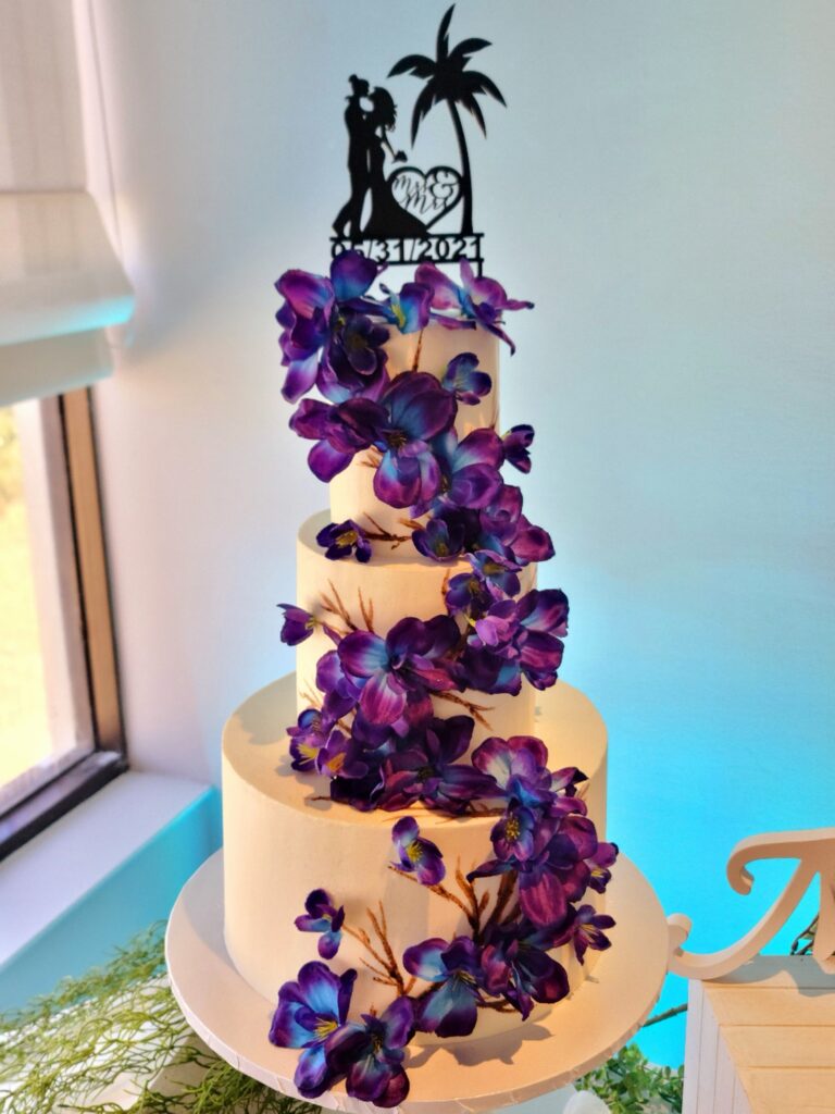 white wedding cake with purple flowers and palm tree cake topper by Butter Bliss Bakeshop