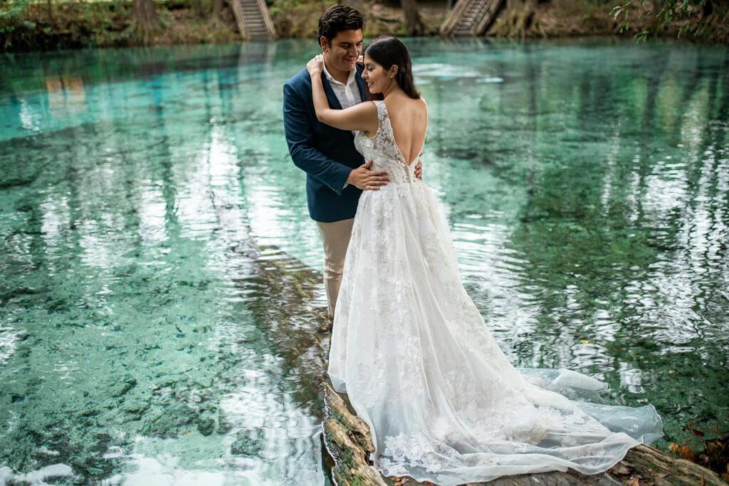 bride and groom embrace by reflection of pond