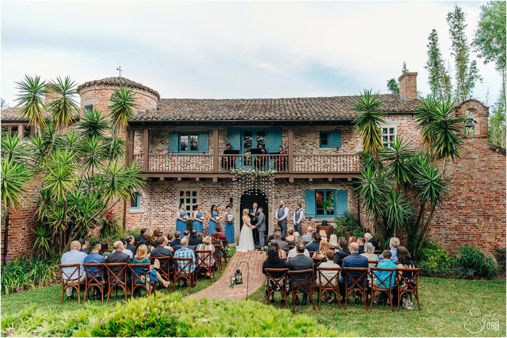 Bride and Groom at their ceremony surrounded by their guests outside of a brick building