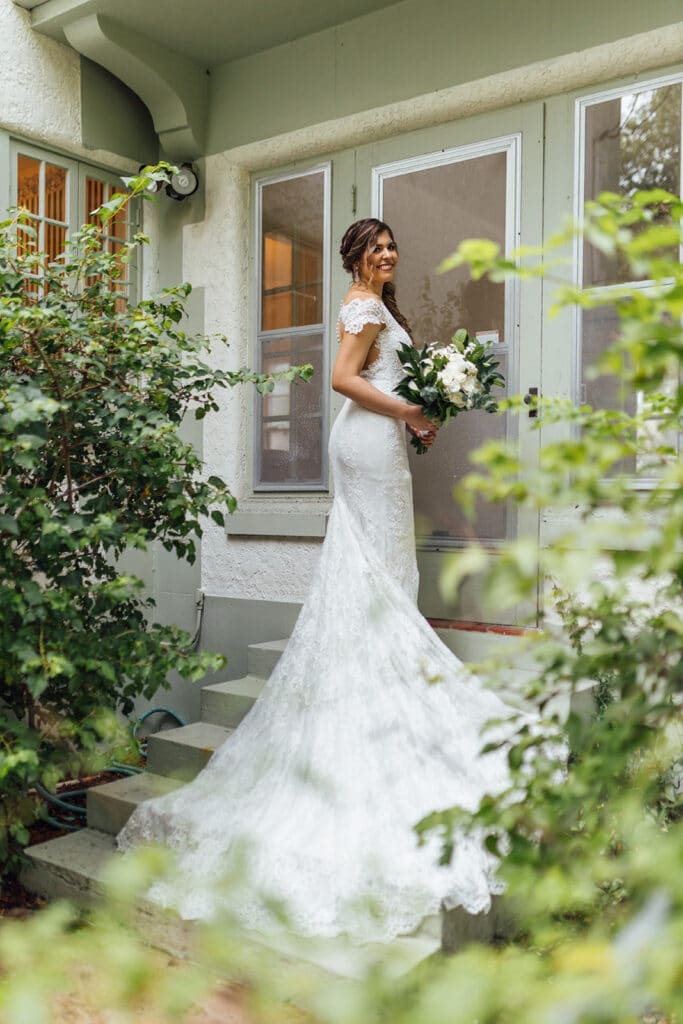 bride walking into house with tropical greenery in the foreground