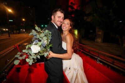 Bride and groom embracing and smiling. It is night time and they are on the street