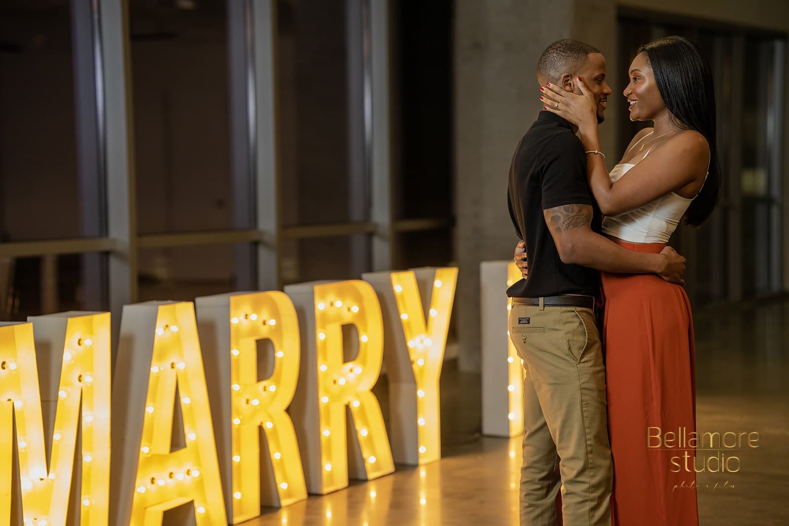 bride and groom-to-be hugging in front of the marry me sign from their downtown orlando marriage proposal.