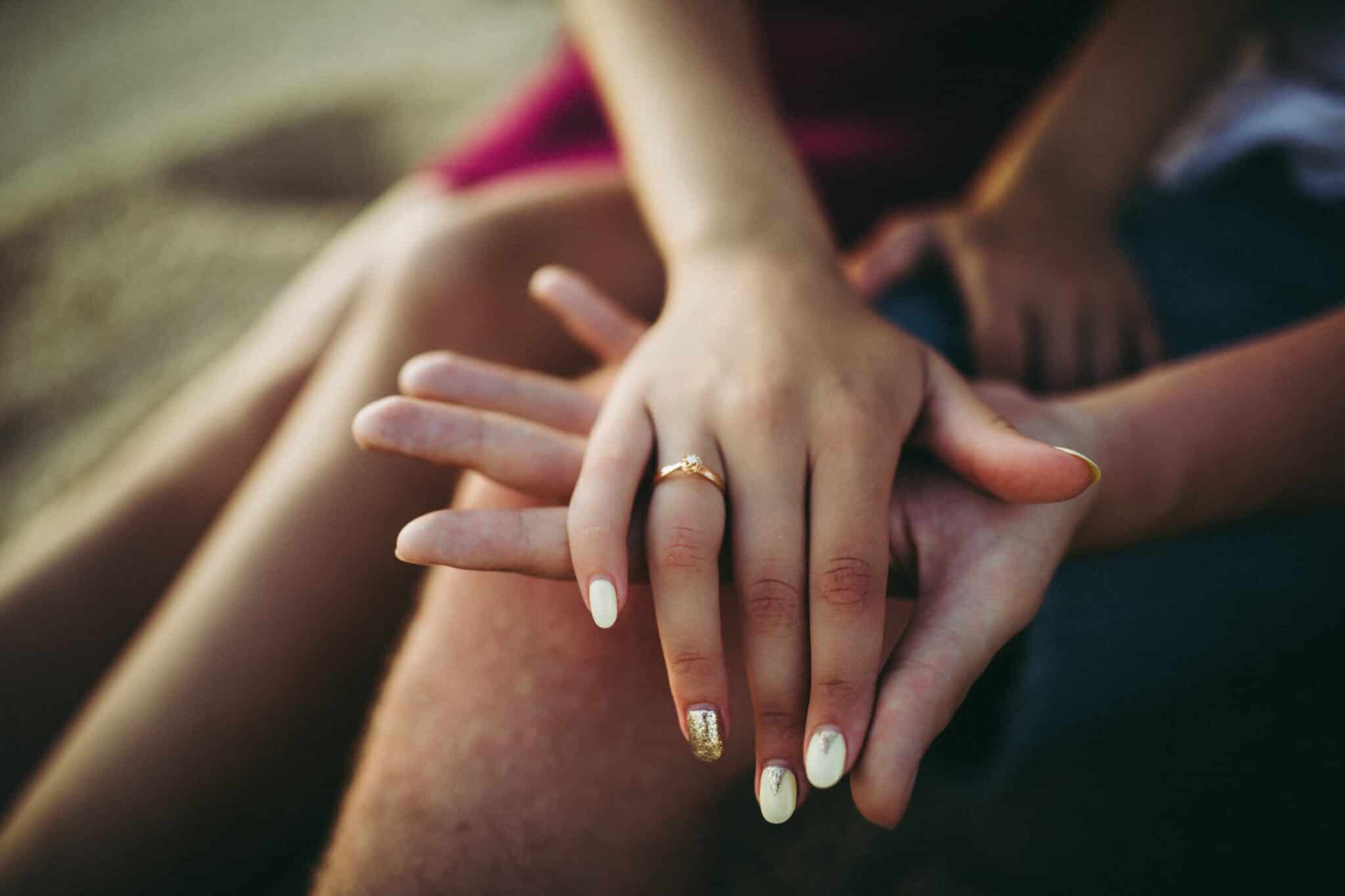 newly engaged couple's hands with engagement ring for 29 best engagement gifts.