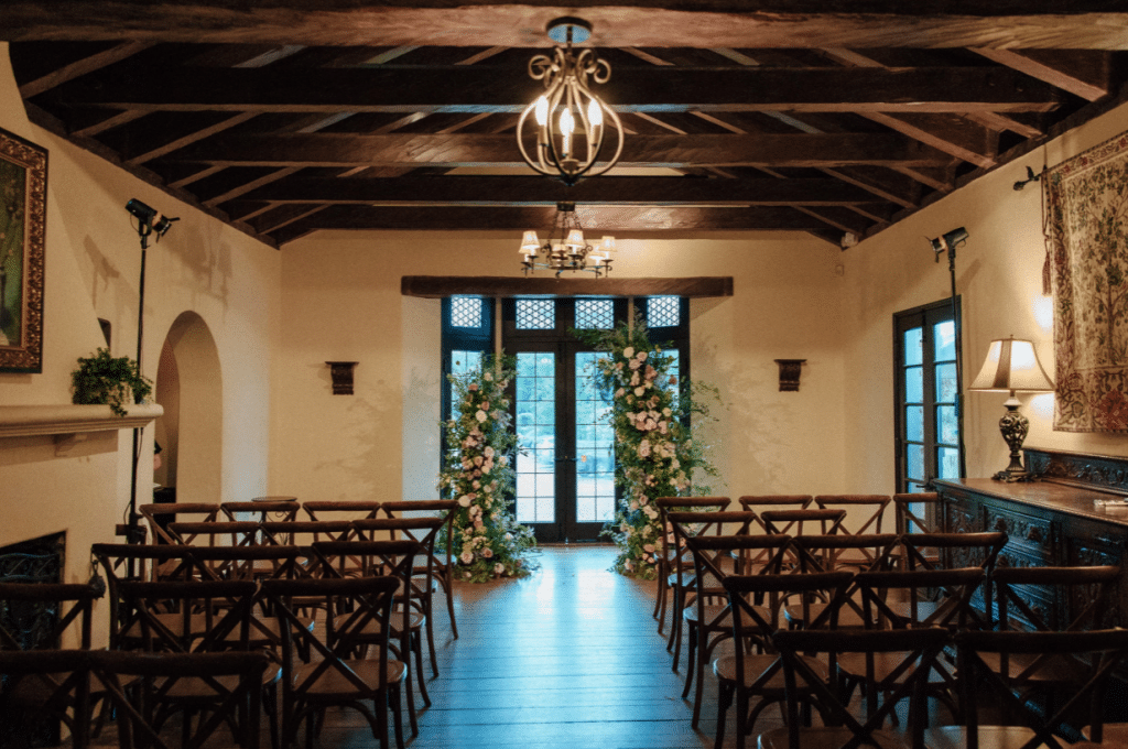 Ceremony area inside a rustic building with a floral arch