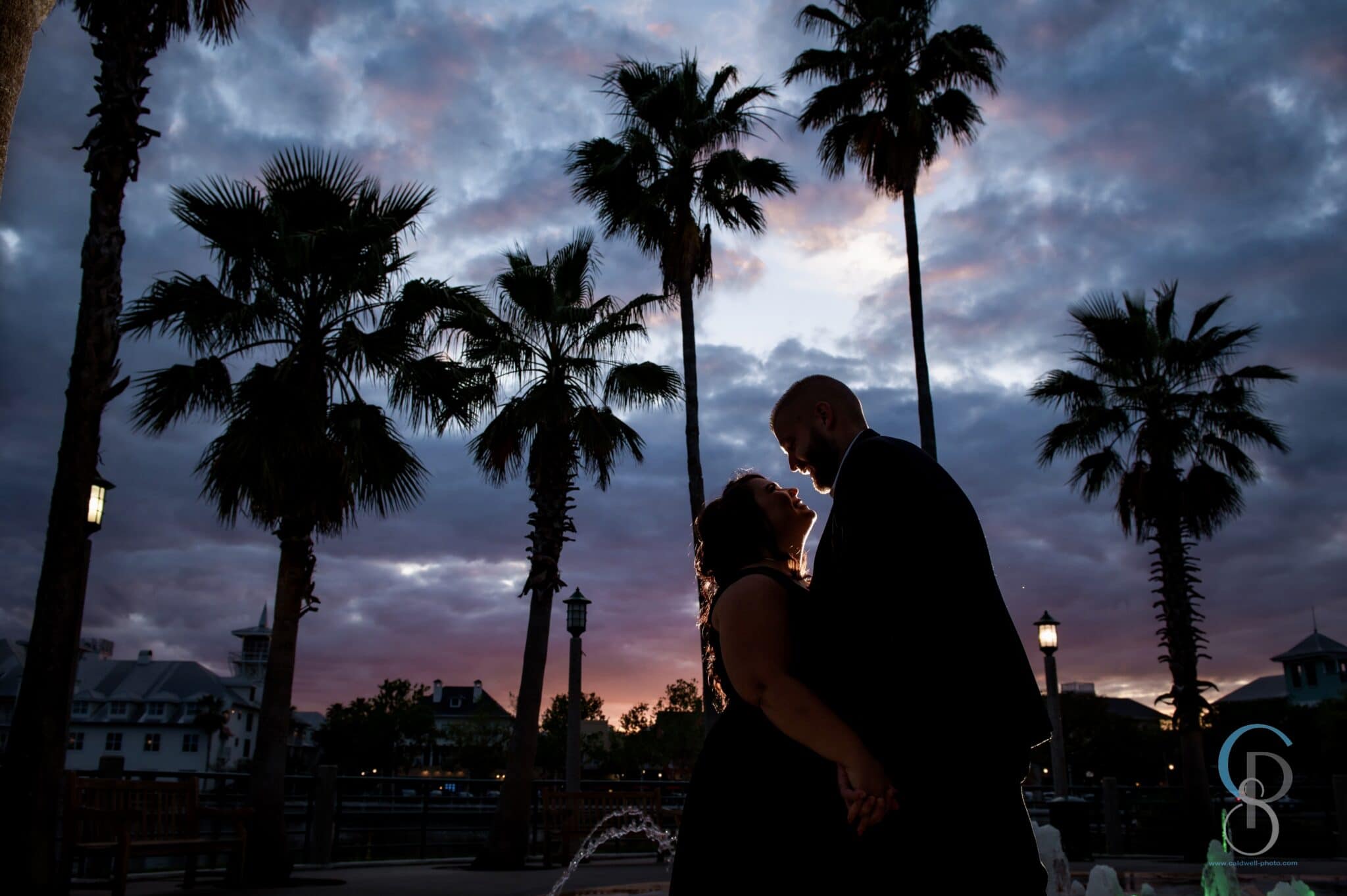 wedding couple silhouetted against sunset and palm trees