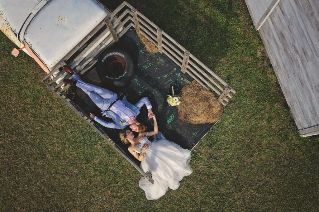 bride and groom laying down in back of a truck