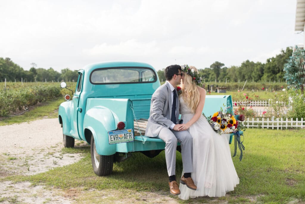 bride and groom kissing in back of teal classic truck