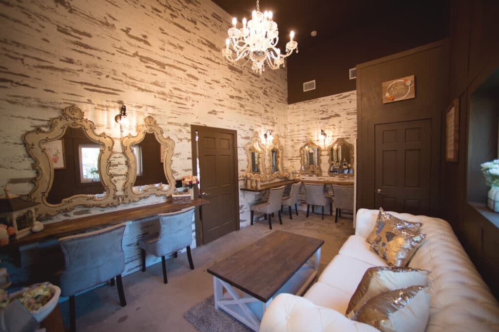 room with white wood walls, classic chandelier, and gold mirrors for getting ready