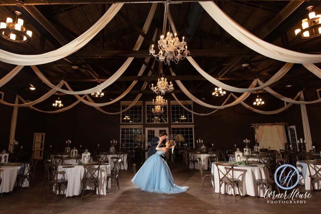 bride and groom dancing in large barn under chandeliers and white drapes