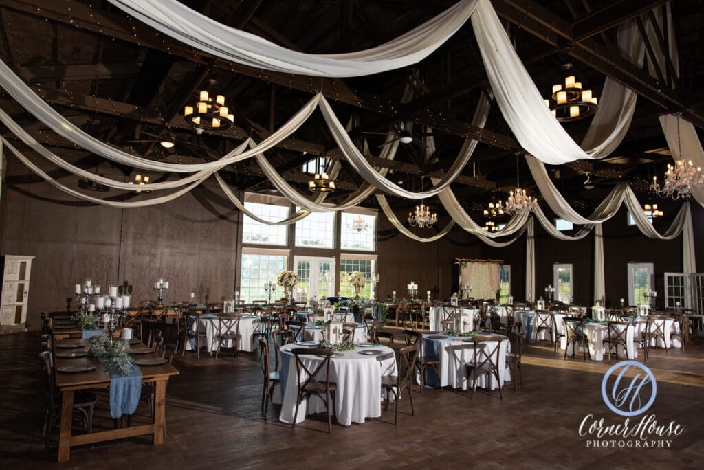 large barn wedding reception with chandeliers and white drapes
