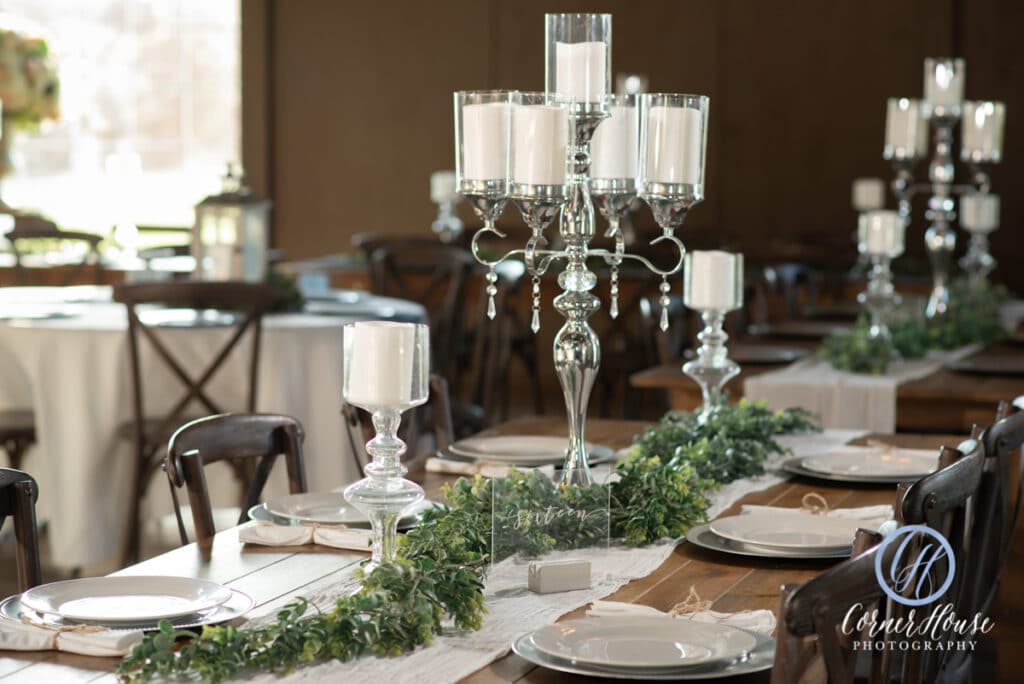 wood table with large white candles and greenery