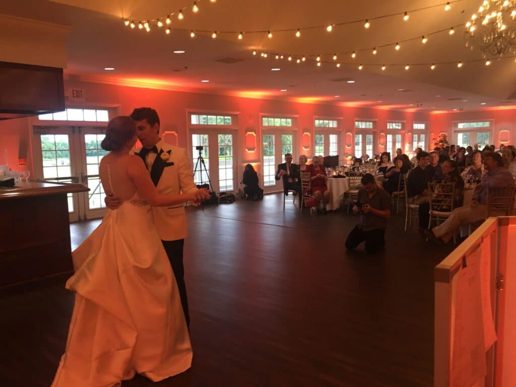 bride and groom dancing in large room with wooden dance floor