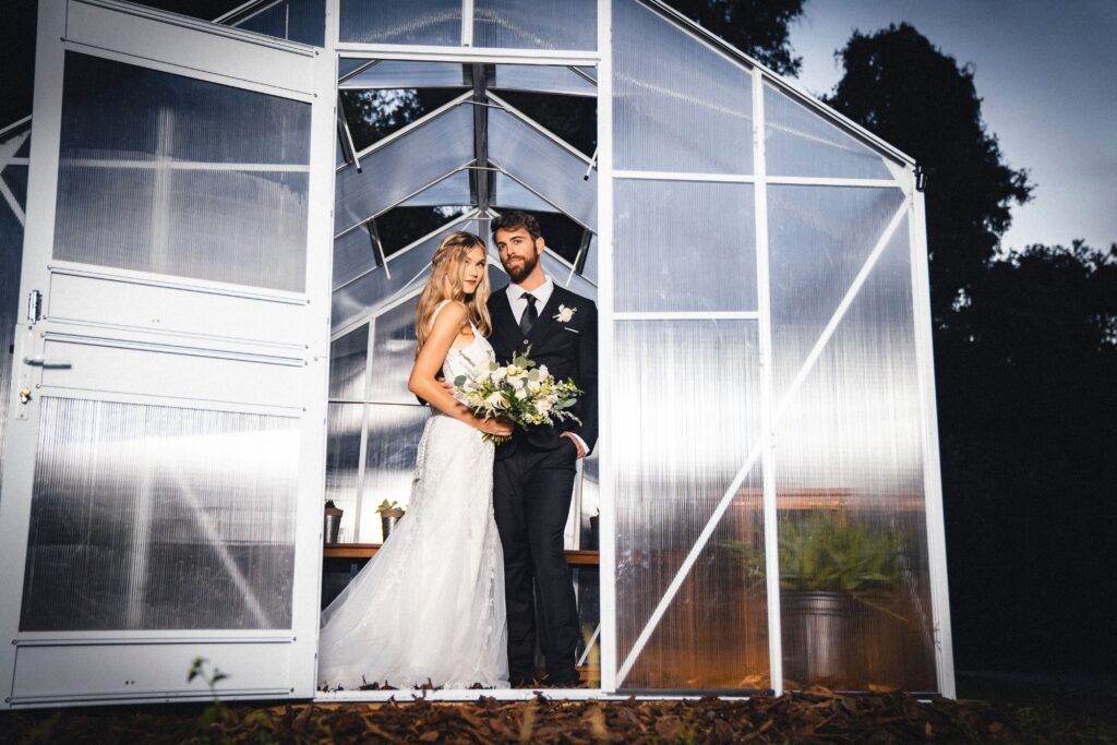 bride and groom standing in doorway to greenhouse