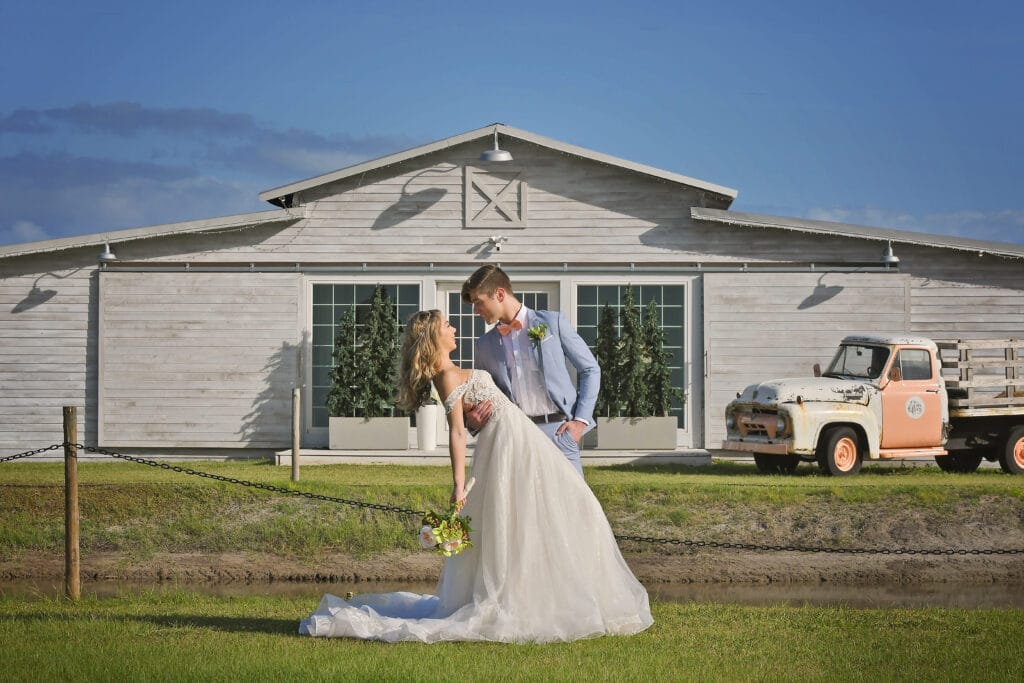 bride and groom in front of rustic barn on wedding day