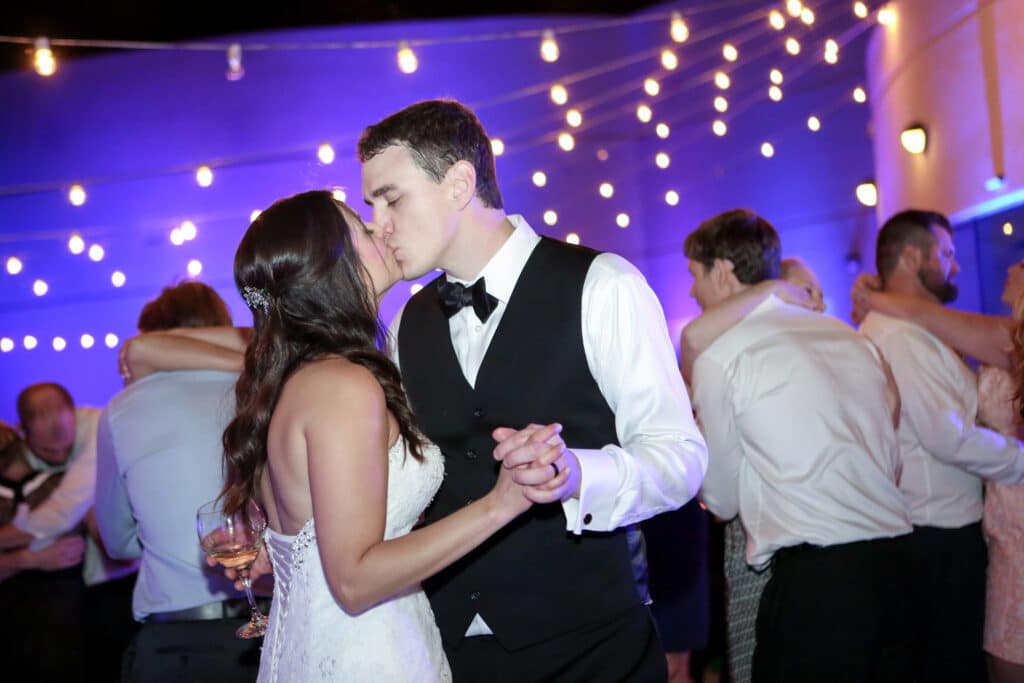 Bride and Groom kiss on dance floor under market lights