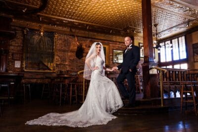 Bride and groom in a rustic venue. There's a dark painting and moose head on the wall