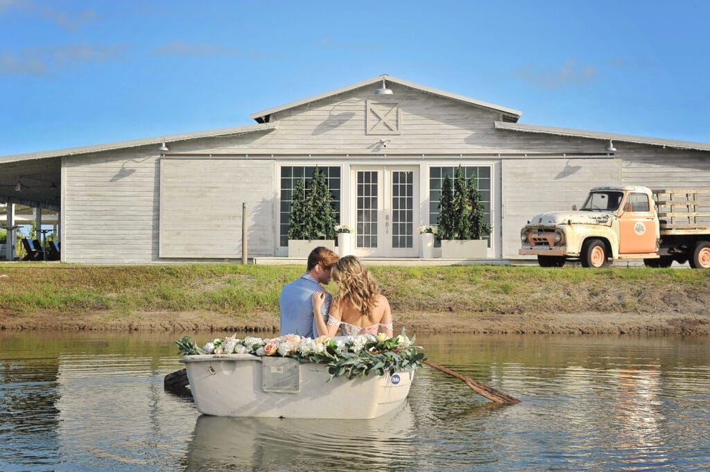 bride and groom in rowboat in front of barn