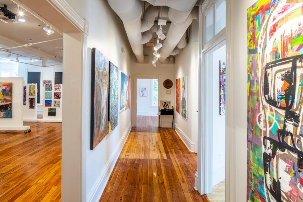 hallway featuring entrances to multiple art galleries with colorful paintings
