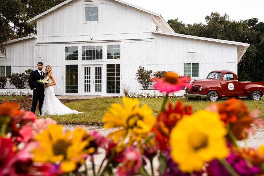 red and yellow wildflowers with white wedding barn behind it
