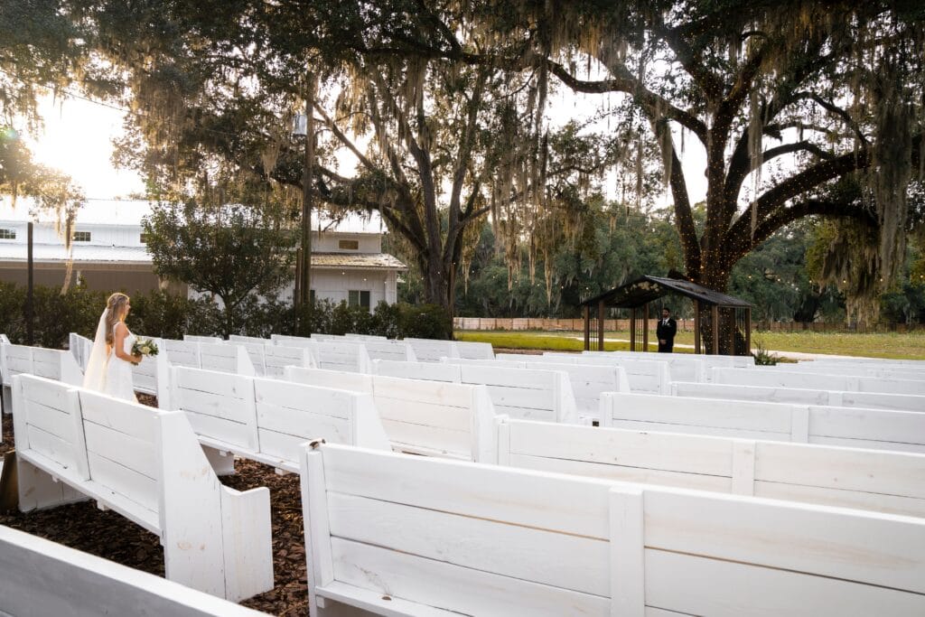 outdoor wedding ceremony location with large oak trees and white benches