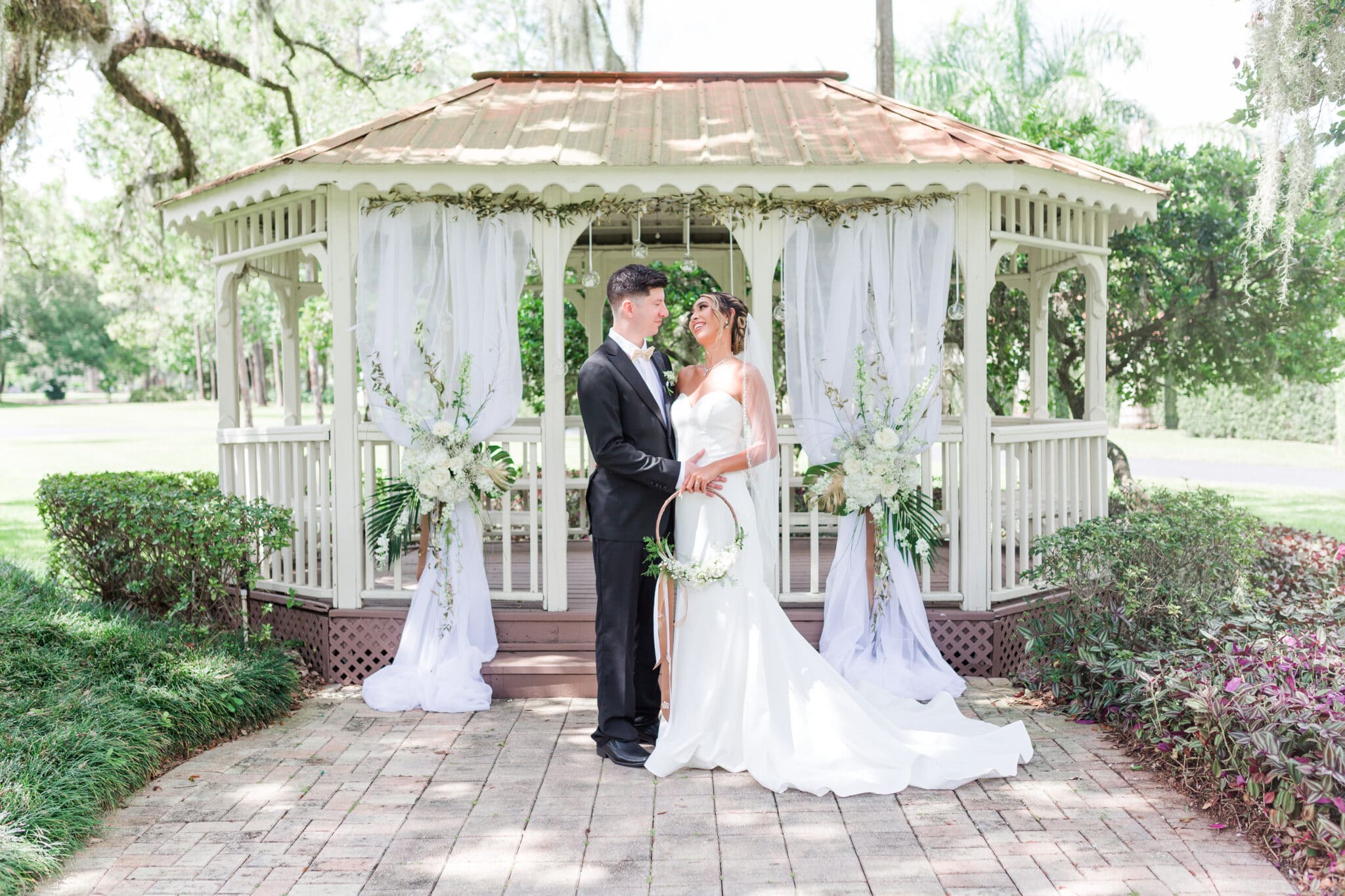 bride and groom standing together in front of the gazebo where their ceremony site is for the glamorous gold wedding inspiration shoot.