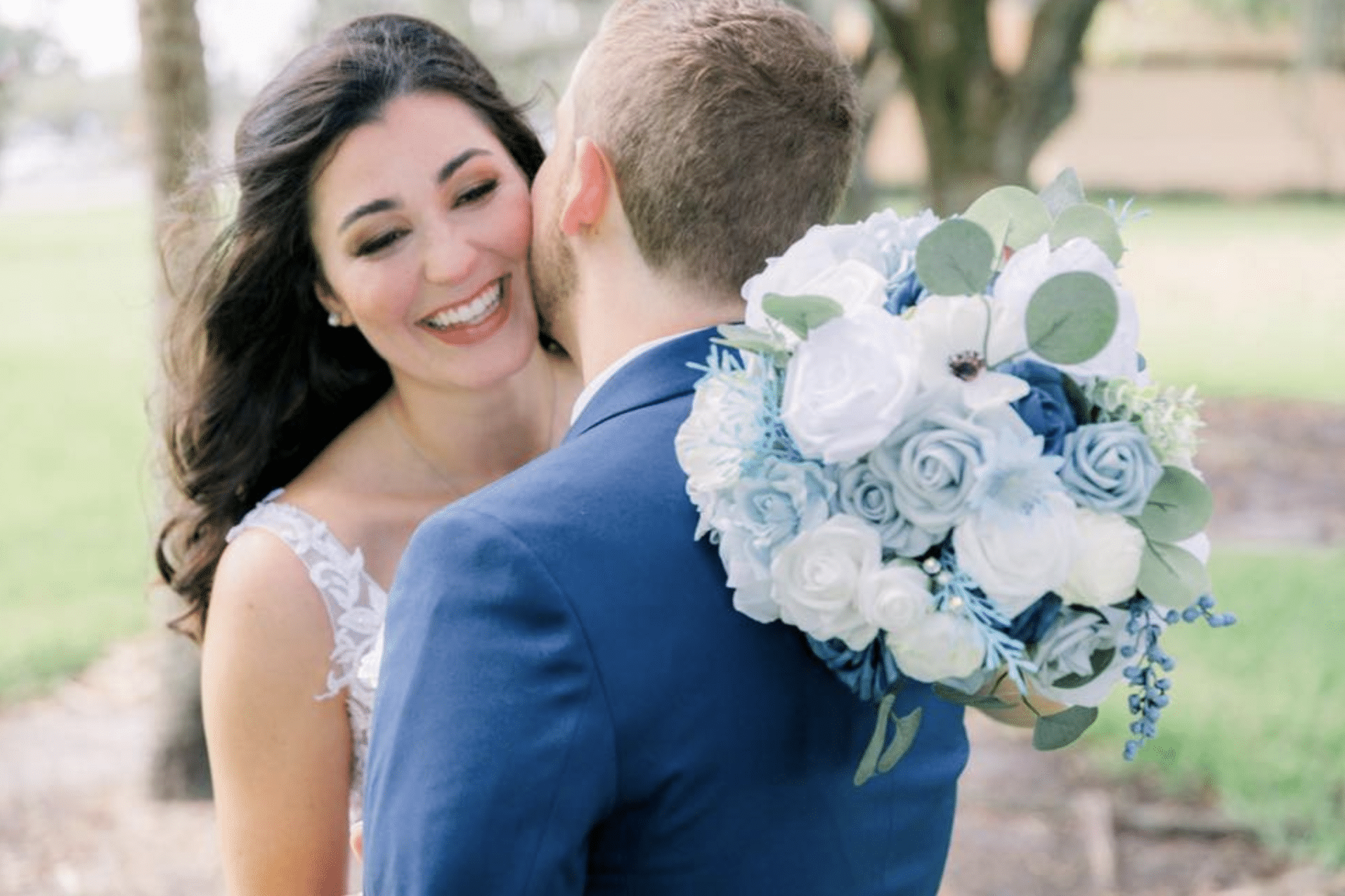 Bride and groom embracing after getting married. She is holding her sage and white color flowers