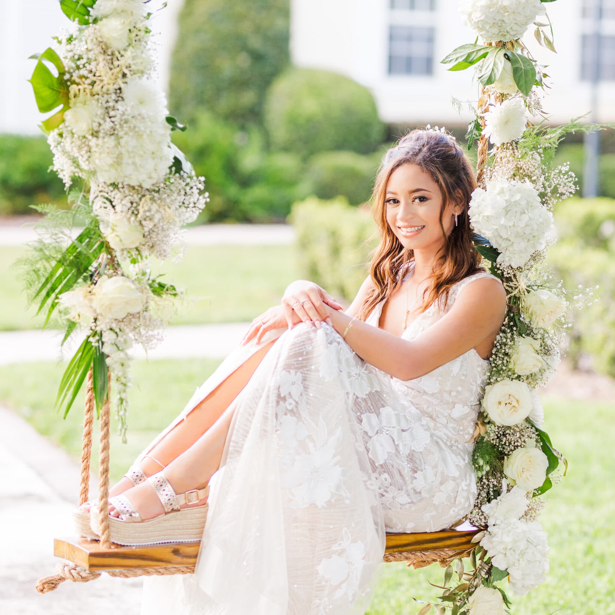bride sitting on the flower swing and smiling.