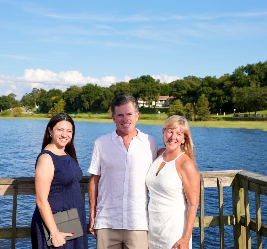 bride and groom with officiant Chrissie from Ceremonies by Chrissie on a pier at a lake
