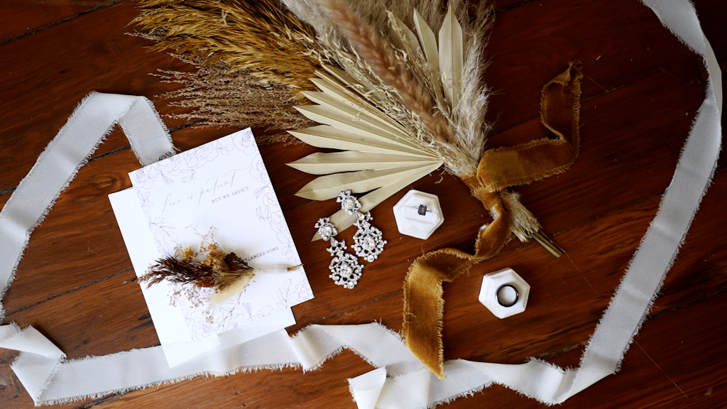 autumnal photo of wedding rings, bouquet, earrings and stationary by Lexi Rabelo Films