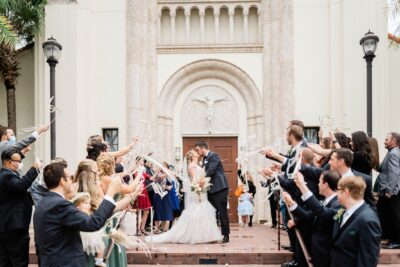 Bride and groom kissing after their wedding. The guests are holding white streamers