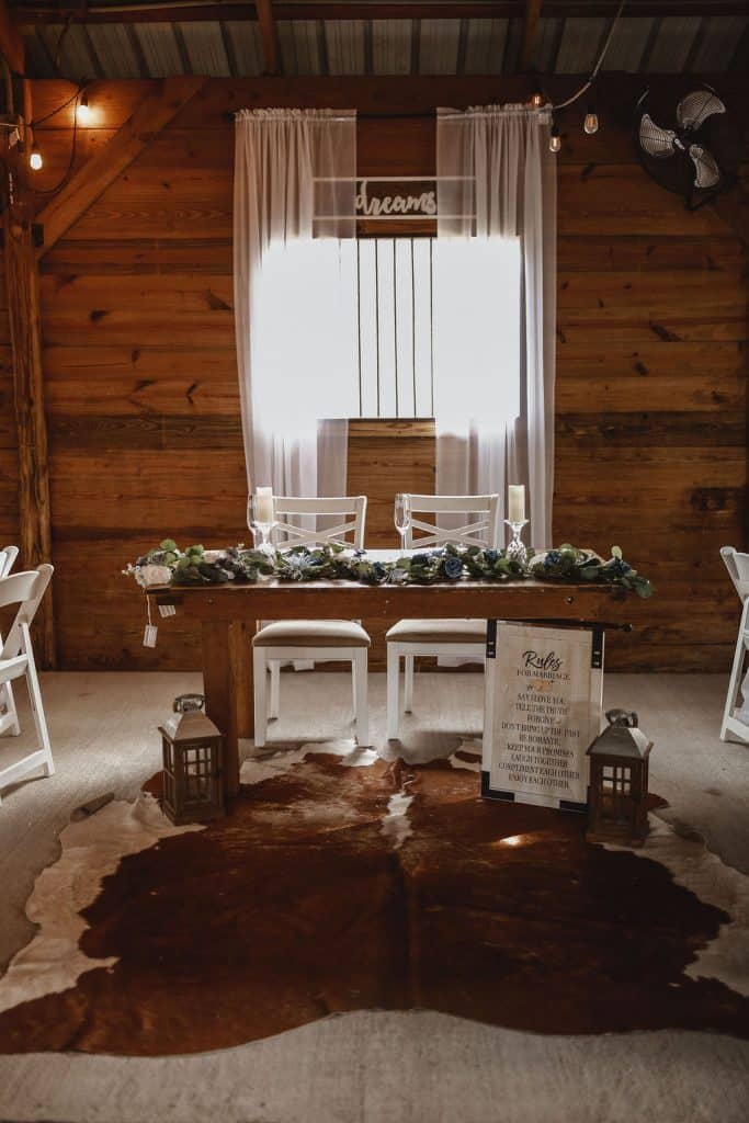 head table, white chairs, animal skin rug, lanterns, large window with white sheer curtains, wood paneling, Still Creek Farm, Central FL