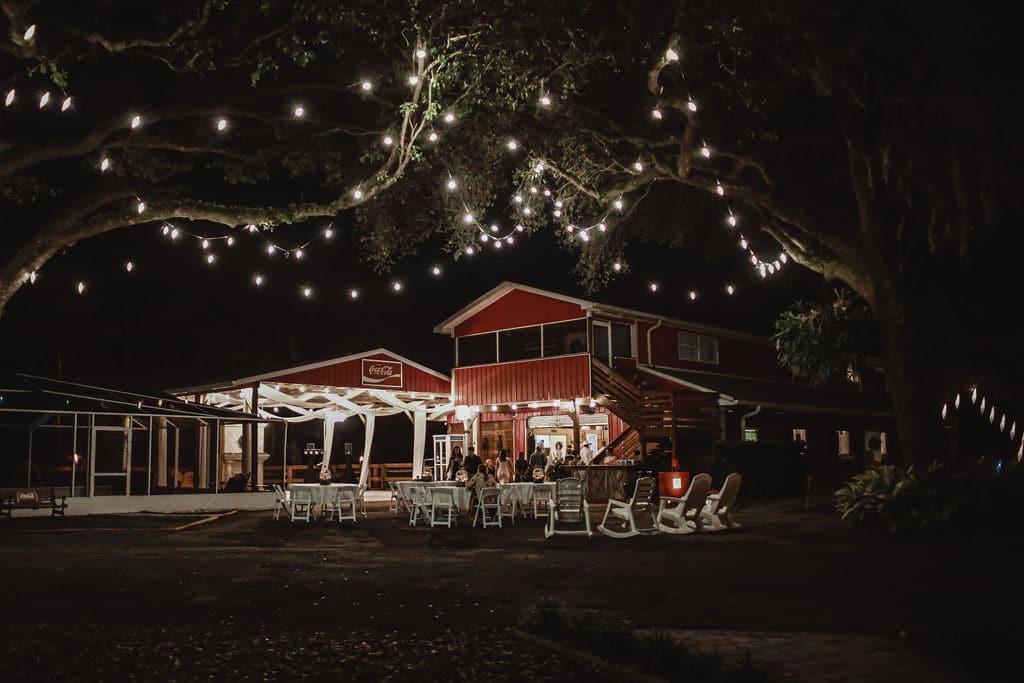 red barn, lights hanging from the trees, nighttime, white chairs, outdoors, Central FL