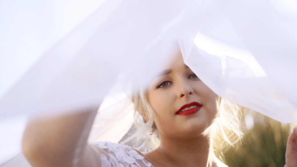 bride with red lip peeking through veil by Lexi Rabelo Films