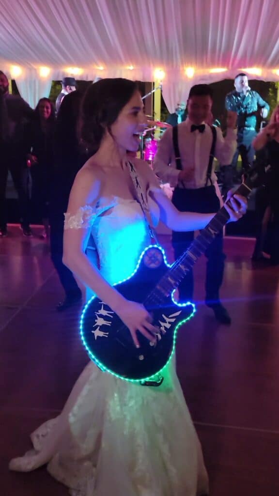 bride playing guitar on dance floor