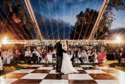Bride and groom dancing under lights on a black and white checkered dance floor