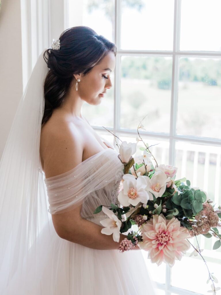 Bride looking out of window with beautiful gown from Definition Bridal